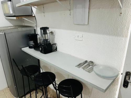 a kitchen with a counter with chairs and a blender at Studio espaçoso em São Paulo no bairro Tucuruvi in Sao Paulo