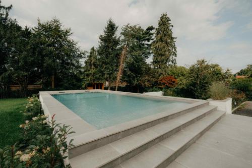 a swimming pool in a yard with trees at Designer Hôtel in Heusy