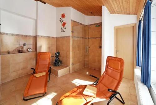 two orange chairs in a bathroom with a shower at Hotel Schachten in Lindberg