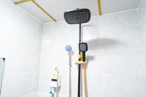 a shower in a white tiled bathroom with a shower at Villaroma Furnished Penthouse Suites in Eldoret