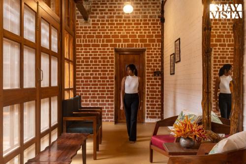 a woman walking down a hallway in a brick building at StayVista at Orchard by the River with Bonfire, BBQ in Karjat