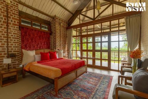 カルジャットにあるStayVista at Orchard by the River with Bonfire, BBQの窓のある部屋に赤いベッドが備わるベッドルーム1室が備わります。