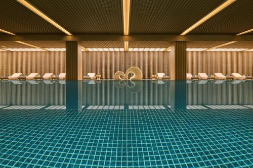 a swimming pool with toilets and chairs in a building at Shu Hua Hotel Tianmu Mountain, Curio Collection By Hilton in Hangzhou