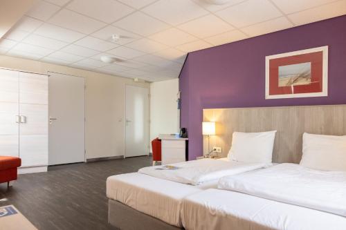 a hotel room with two beds and a purple wall at Fletcher Hotel - Restaurant de Cooghen in De Koog