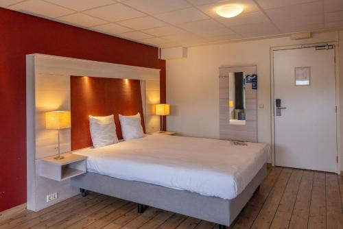 a bedroom with a large white bed with red walls at Fletcher Hotel - Restaurant de Cooghen in De Koog