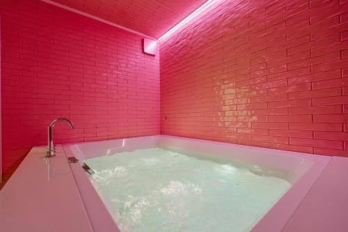 a bathroom with a hot tub with a red brick wall at Designer Hôtel in Heusy