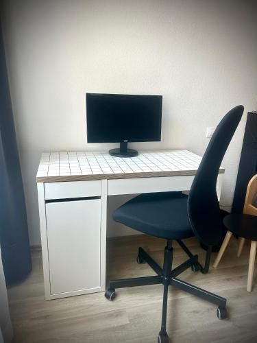 a computer monitor sitting on a desk with a chair at Ubytování v srdci Písku in Písek