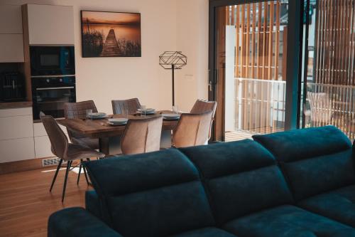a living room with a couch and a table and chairs at MOLO LIPNO RESIDENCE in Lipno nad Vltavou