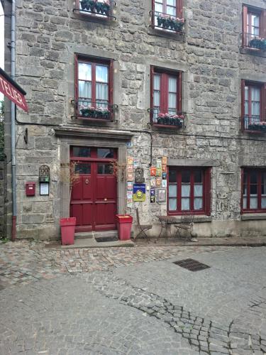 a stone building with red doors and windows at Chalet Emma appartement tout équipé et refait a neuf dans une résidence 3 étoiles in Besse-et-Saint-Anastaise