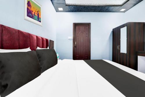 a bedroom with a large bed with a red headboard at Hotel O Dharohar in Rishīkesh