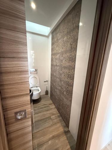 a bathroom with a toilet and a wooden door at Élégant appartement avec parking privé proche aéroport et centre ville Tunis Laouina in El Aouina