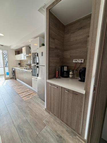 a kitchen with wooden walls and a white refrigerator at Élégant appartement avec parking privé proche aéroport et centre ville Tunis Laouina in El Aouina