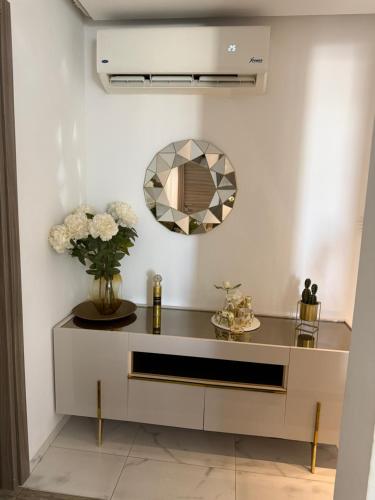 a dressing table with a mirror and flowers on it at Élégant appartement avec parking privé proche aéroport et centre ville Tunis Laouina in El Aouina