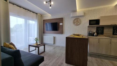 a kitchen and a living room with a couch and a table at Q Apart Orion - dwupokojowy, klimatyzowany apartament przy Manufakturze z darażem Gratis, FV in Łódź