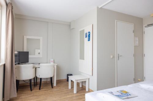 a white room with a desk and two white chairs at Fletcher Hotel - Restaurant de Cooghen in De Koog