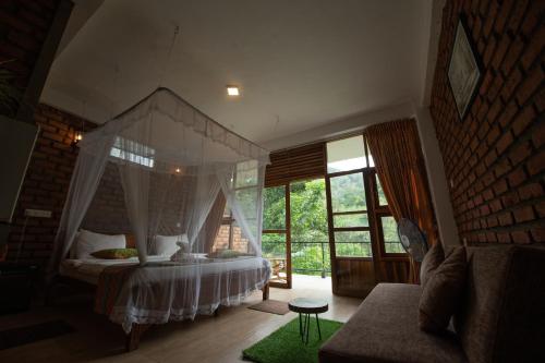 a bedroom with a canopy bed and a couch at Ayubo Ella - Bed & Breakfast in Ella