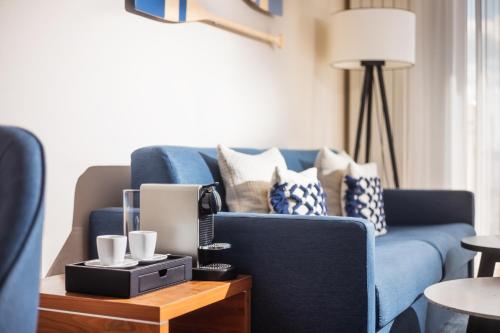 a living room with a blue couch with pillows at Lindner Hotel Boltenhagen, part of JdV by Hyatt in Boltenhagen