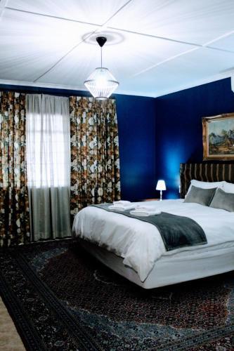 a bedroom with blue walls and a large bed at Anyskop Guest Farm in Langebaanweg