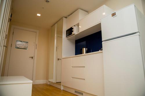 a kitchen with white cabinets and a refrigerator at DOWNTOWN Centre in Batumi Aparthotel Orbi City in Batumi