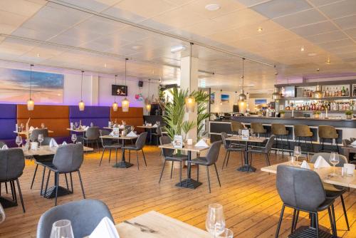 a restaurant with tables and chairs and a bar at Fletcher Hotel - Restaurant de Cooghen in De Koog
