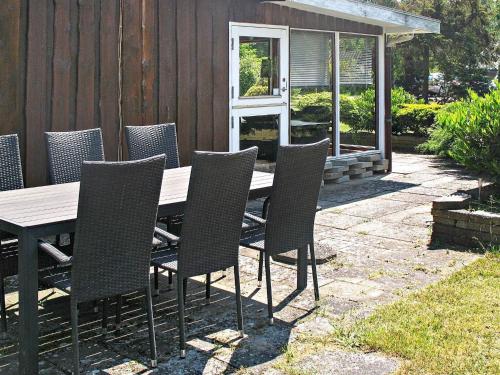a wooden table and chairs on a patio at 6 person holiday home in Væggerløse in Bøtø By