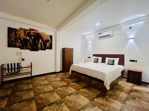 a bedroom with a bed and paintings on the wall at Mariners Cove Villa in Tangalle