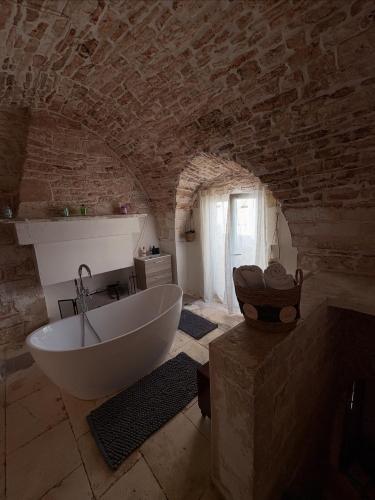 a bathroom with a white tub in a stone wall at Liuzzi ross in Martina Franca