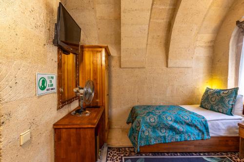 a small bedroom with a bed and a tv at Walnut House in Goreme