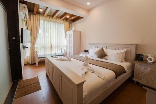 une chambre avec un grand lit avec deux oiseaux dessus dans l'établissement Grandeur De Sanchi Resort, à Calangute