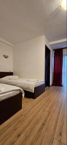 a hotel room with two beds and a wooden floor at Hotel Bran Dracula in Bran