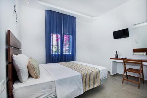 ein Schlafzimmer mit einem Bett, einem Fenster und einem Schreibtisch in der Unterkunft Petini's Place in Fira