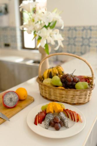 a plate of food on a counter with a basket of fruit at Casa Suneos 4-BHK Villa With Private Pool & Lift Near Popular Restaurants in Siolim