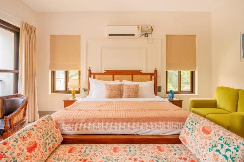 a bedroom with a bed and a green chair at Casa Suneos 4-BHK Villa With Private Pool & Lift Near Popular Restaurants in Siolim