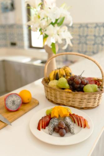 a plate of food on a counter with a basket of fruit at Casa Suneos 4-BHK Villa With Private Pool & Lift Near Popular Restaurants in Siolim