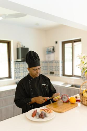 a man in a kitchen preparing food on a cutting board at Casa Suneos 4-BHK Villa With Private Pool & Lift Near Popular Restaurants in Siolim
