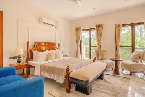 a bedroom with a large bed and a blue chair at Casa Suneos 4-BHK Villa With Private Pool & Lift Near Popular Restaurants in Siolim