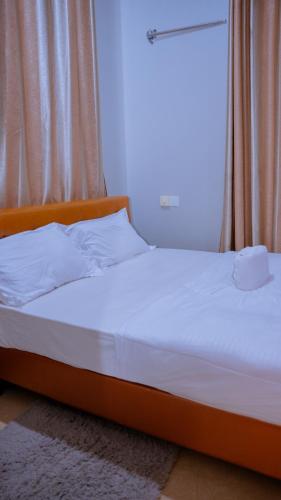 a bed in a room with a window with a white mattress at Hotel Rolax - Dodoma in Nkunjila