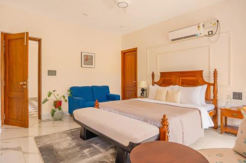 a bedroom with a bed and a blue chair at Casa Suneos 4-BHK Villa With Private Pool & Lift Near Popular Restaurants in Siolim