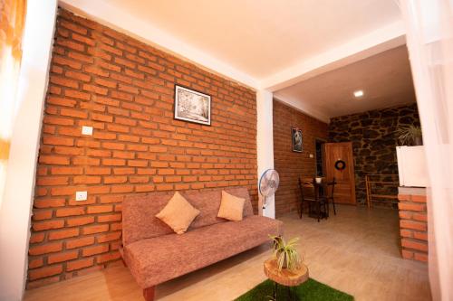 a living room with a brick wall and a couch at Ayubo Ella - Bed & Breakfast in Ella