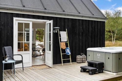 a black shed with a white door and a deck at HA386-Hals-Merkurvej-91 in Hals