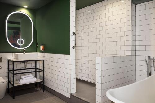 a bathroom with a tub and a sink and a mirror at Malmaison Newcastle in Newcastle upon Tyne