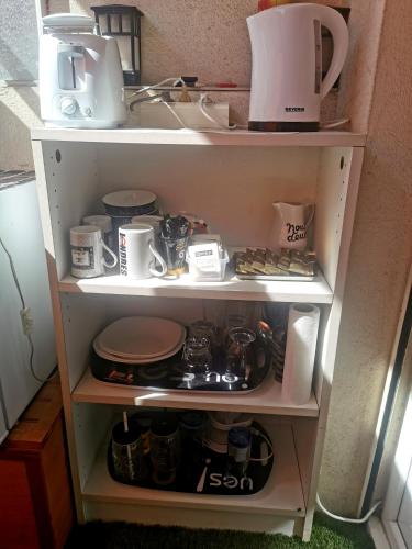 a kitchen shelf with dishes and appliances in it at CHAMBRE CHEZ L'HABITANT - ROOM IN THE OWNER'S APARTMENT in Nice