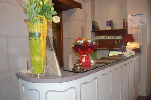a counter with two vases with flowers on it at Logis Hôtel & Restaurant - Le Bretagne in Sillé-le-Guillaume