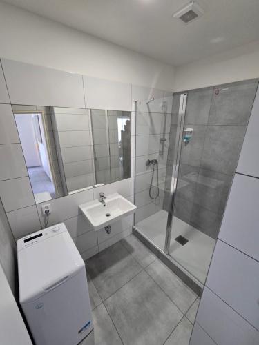 a white bathroom with a shower and a sink at Spirit apartments Brno, with parking in Brno