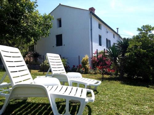 three white chairs sitting in the grass in front of a building at Gemütliches Ferienhaus Viskic in Supetarska Draga