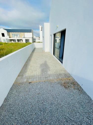 a pathway leading to a white building with a door at 44 Staycation Beach-house in Britannia Bay