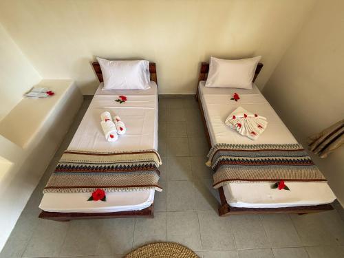 two beds in a small room with towels on them at Hostel 197 in Nungwi