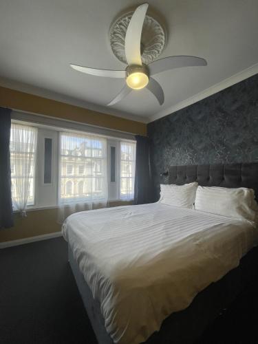 a bedroom with a white bed with a ceiling fan at The Montana in Torquay