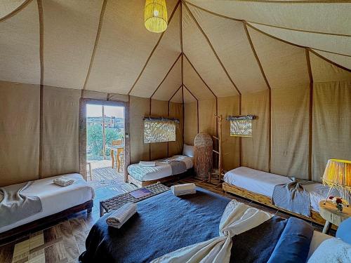 a room with a tent with beds and a window at Agafay, La Ferme Nomade Bivouac in El Karia