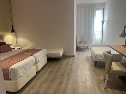 a hotel room with two beds and a desk at Silken Rona Dalba in Salamanca